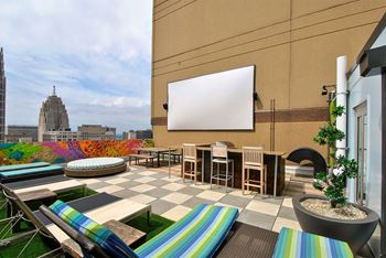 a rooftop terrace with tables and chairs and a projection screen
